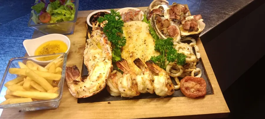 A shared seafood board with grilled lobster, fish and chips