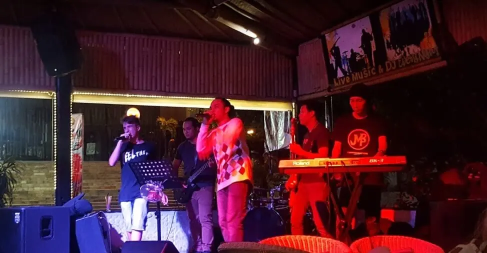 A live band performing on the Bamboo stage under red and magenta lights