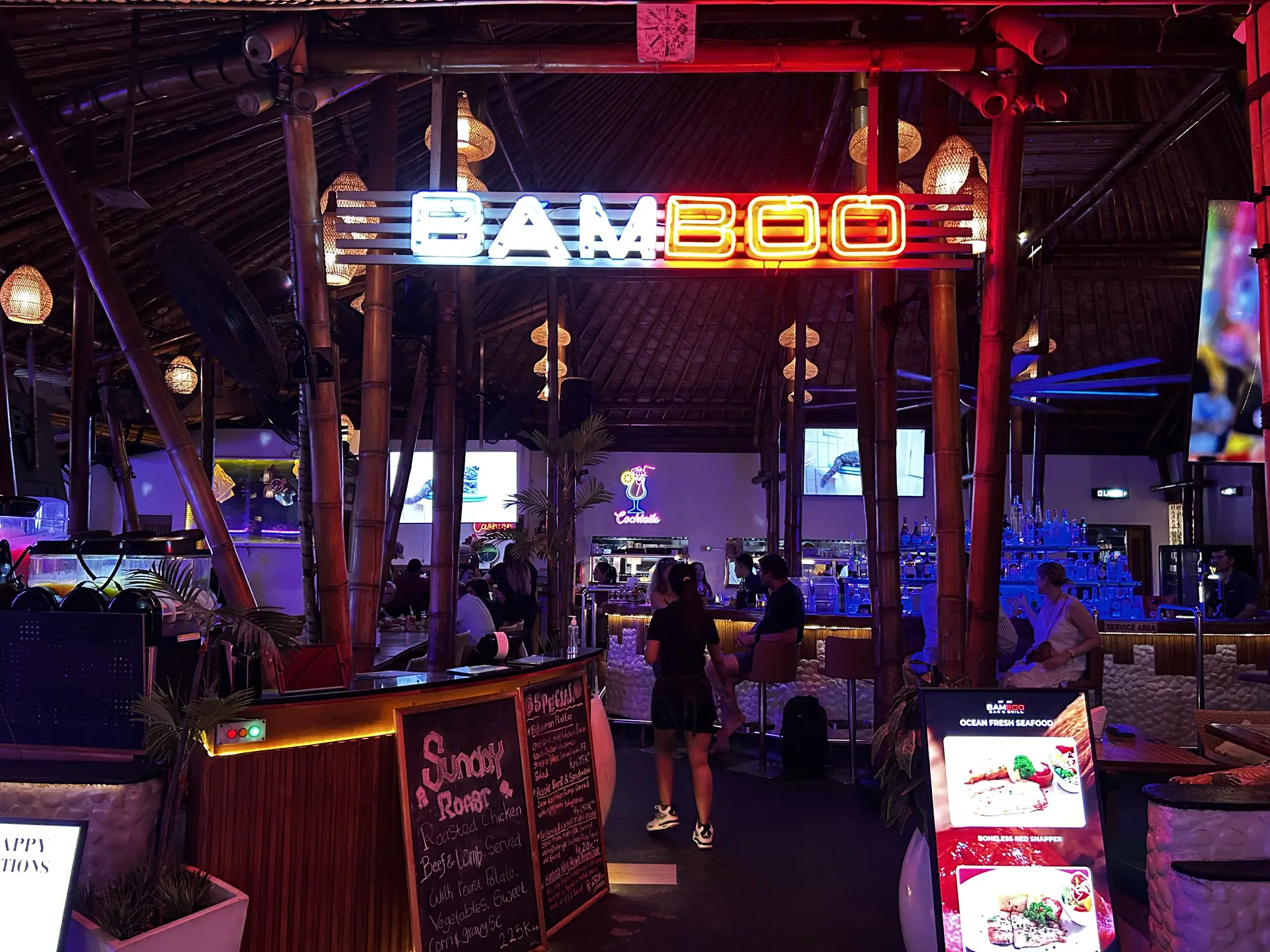 Inside Bamboo at night, the neon sign glowing over a full room